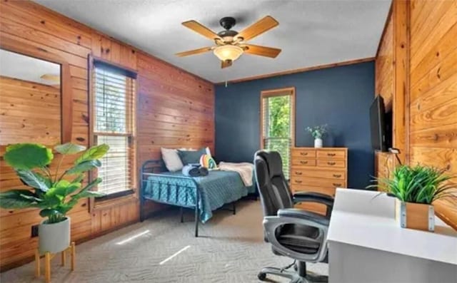 carpeted bedroom featuring ceiling fan and wood walls