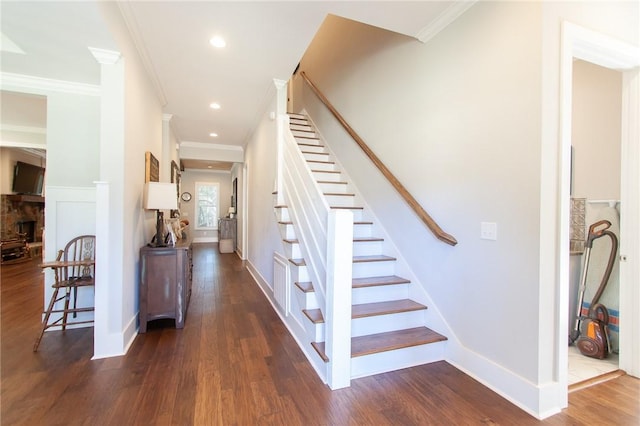 stairway with a fireplace, wood-type flooring, and ornamental molding