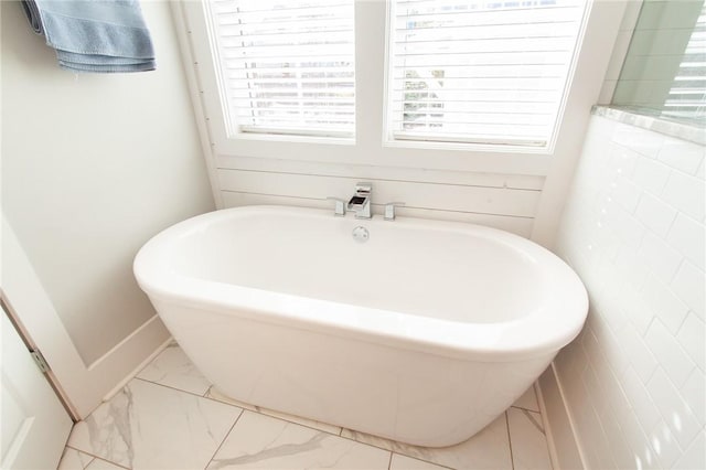 bathroom with a bathing tub and a healthy amount of sunlight