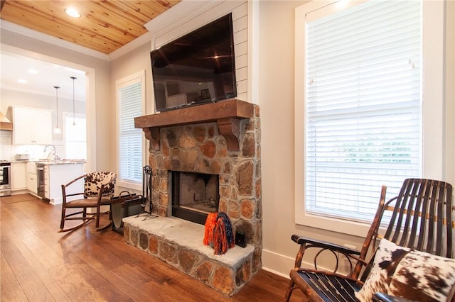 living area with sink, wooden ceiling, ornamental molding, a fireplace, and hardwood / wood-style floors