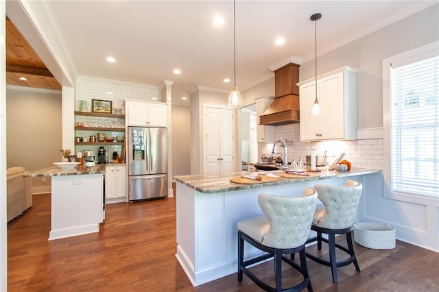 kitchen with white cabinetry, stainless steel fridge, decorative light fixtures, and kitchen peninsula