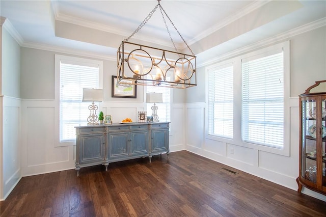 dining area featuring a tray ceiling, crown molding, dark wood-type flooring, and an inviting chandelier