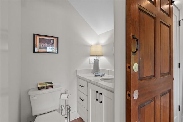 bathroom featuring vanity, lofted ceiling, and toilet