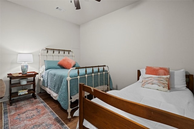 bedroom with ceiling fan, visible vents, and wood finished floors