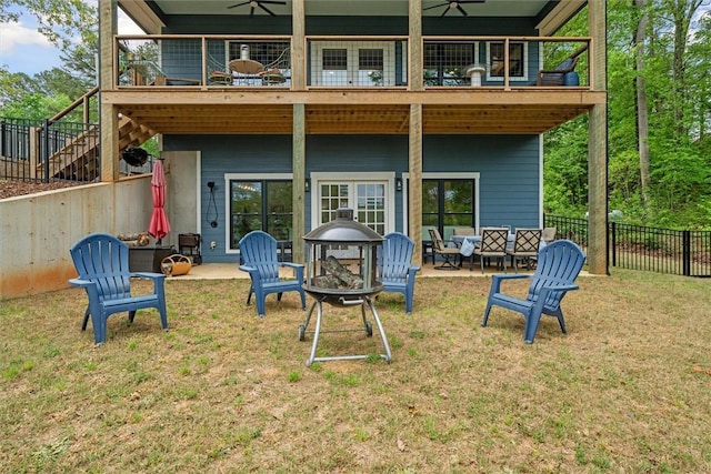 rear view of house featuring a lawn, fence, a ceiling fan, and a fire pit