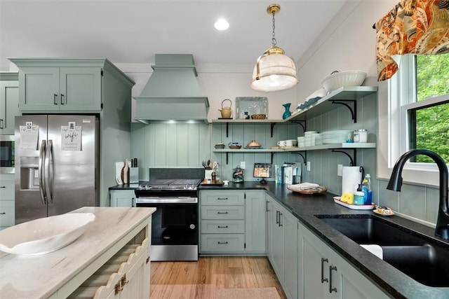 kitchen featuring open shelves, custom range hood, a sink, appliances with stainless steel finishes, and hanging light fixtures