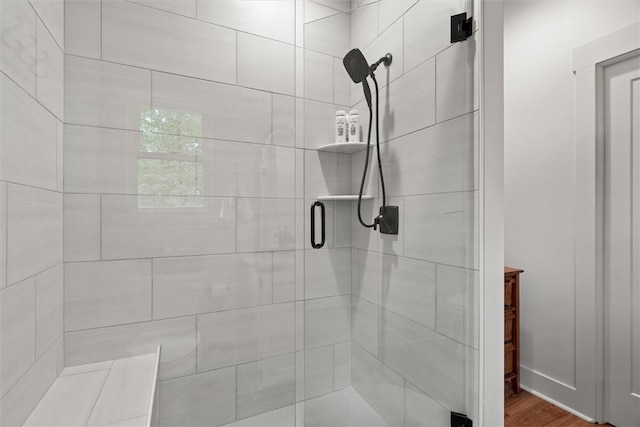 bathroom with wood finished floors and a shower stall
