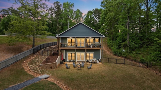 back of property at dusk featuring french doors, a lawn, a fenced backyard, a patio, and stairs