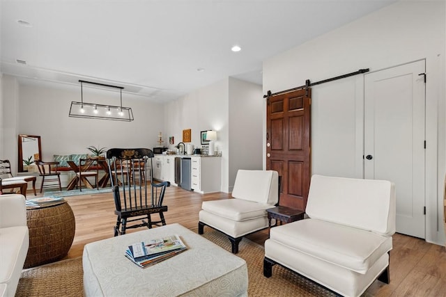 living room featuring light wood-type flooring, a barn door, and recessed lighting