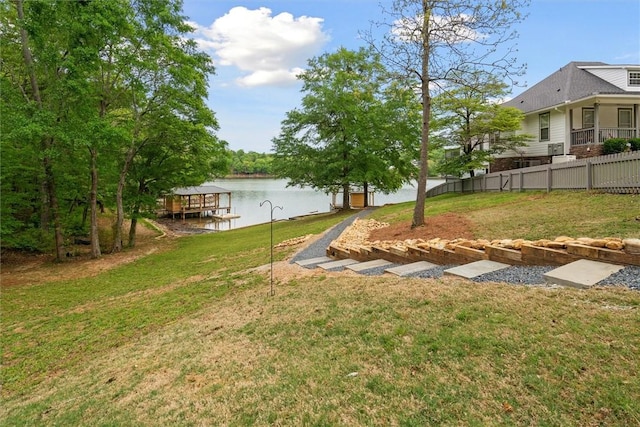 view of yard featuring fence, a water view, and a dock