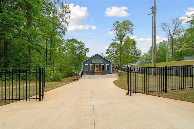 view of community with concrete driveway, a yard, and fence