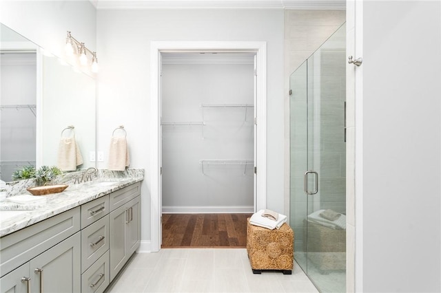 full bath featuring a stall shower, a sink, baseboards, and double vanity