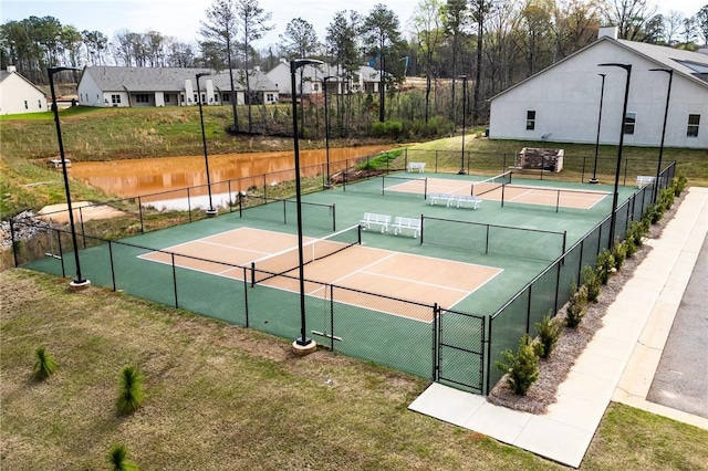 view of tennis court with fence and a lawn