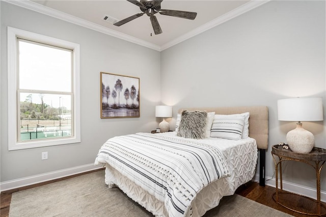 bedroom featuring crown molding, visible vents, ceiling fan, wood finished floors, and baseboards
