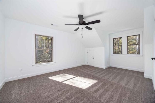 additional living space featuring ceiling fan, lofted ceiling, dark carpet, and plenty of natural light