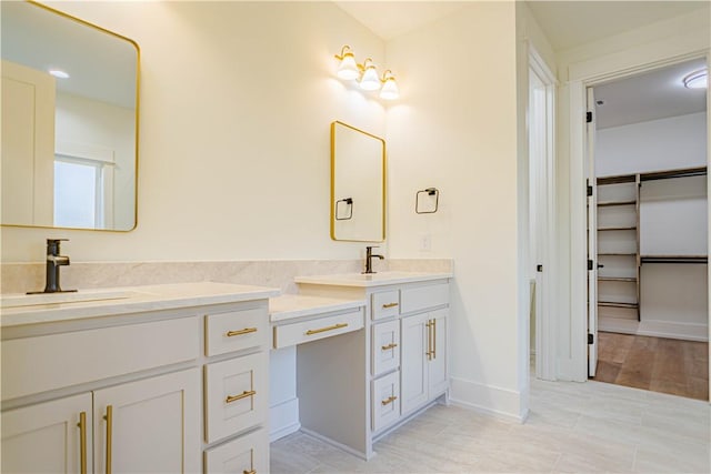 2307 Alpha Dr, Phenix City, AL 36867 - bathroom featuring double vanity, a spacious closet, baseboards, and a sink