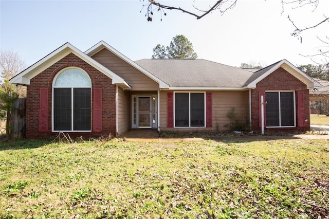 back of house featuring brick siding and a lawn