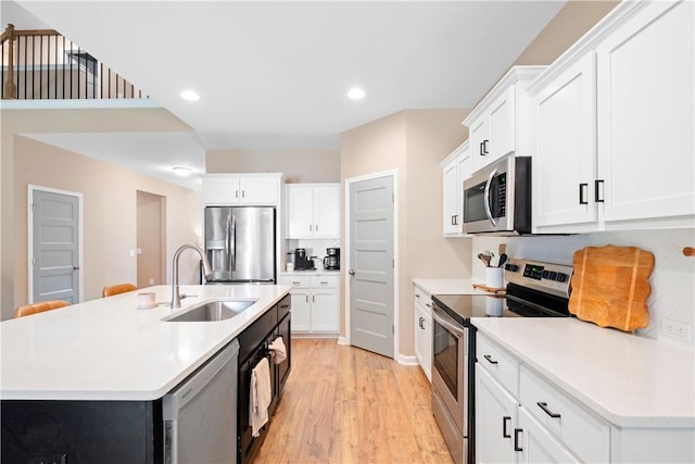 kitchen with white cabinets, an island with sink, stainless steel appliances, and sink