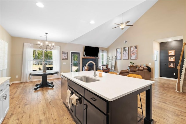 kitchen with white cabinetry, sink, light hardwood / wood-style flooring, a kitchen island with sink, and ceiling fan with notable chandelier