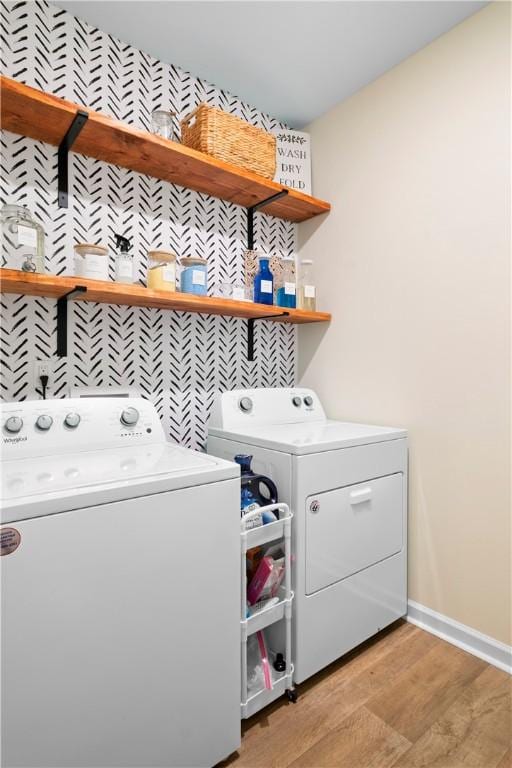 clothes washing area with washer and clothes dryer and light hardwood / wood-style flooring