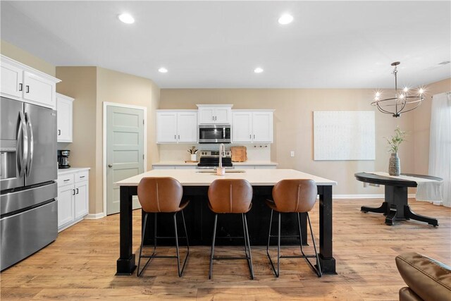 kitchen featuring white cabinets, appliances with stainless steel finishes, pendant lighting, and sink