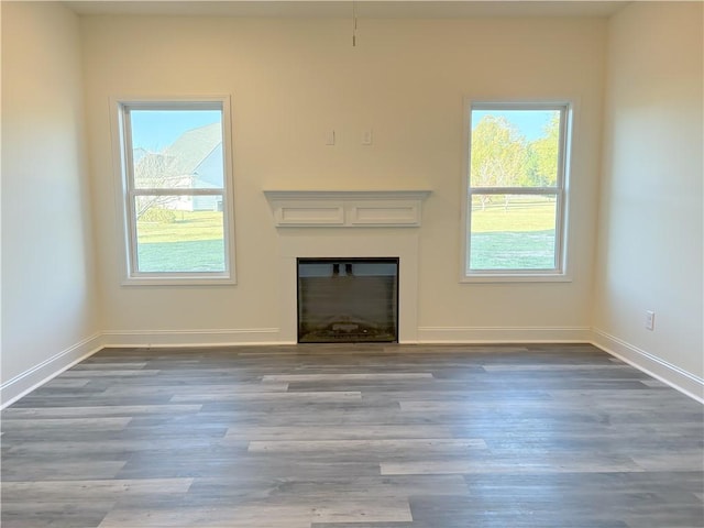 unfurnished living room featuring a healthy amount of sunlight and dark hardwood / wood-style flooring