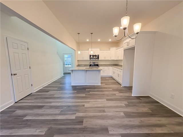 kitchen featuring appliances with stainless steel finishes, a kitchen island with sink, decorative light fixtures, white cabinets, and a chandelier