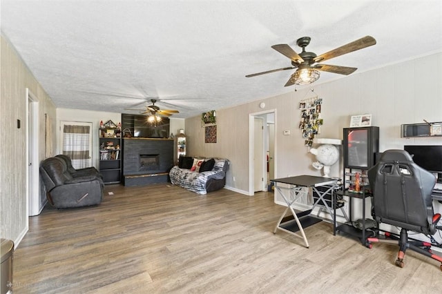 1066 Brown St, Valley, AL 36854 - living room with a ceiling fan, wood finished floors, a fireplace with raised hearth, and a textured ceiling