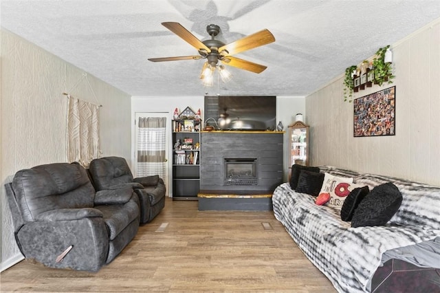 1066 Brown St, Valley, AL 36854 - living room featuring a textured ceiling, wood finished floors, ceiling fan, and a fireplace with raised hearth