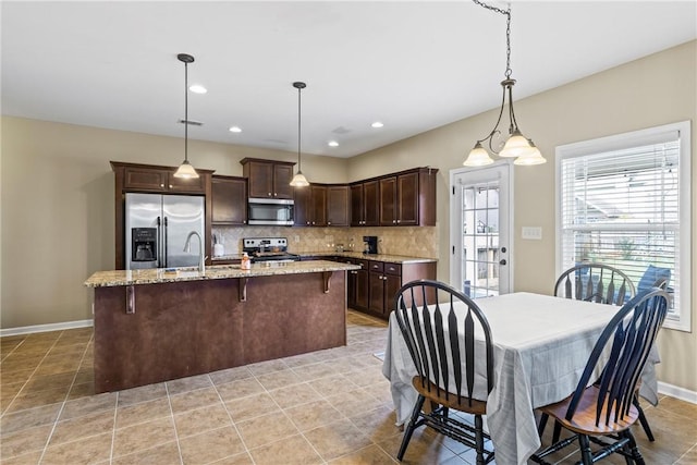 331 Lightness Dr, Auburn, AL 36830 - kitchen with stainless steel appliances, dark brown cabinetry, tasteful backsplash, a kitchen breakfast bar, and an island with sink