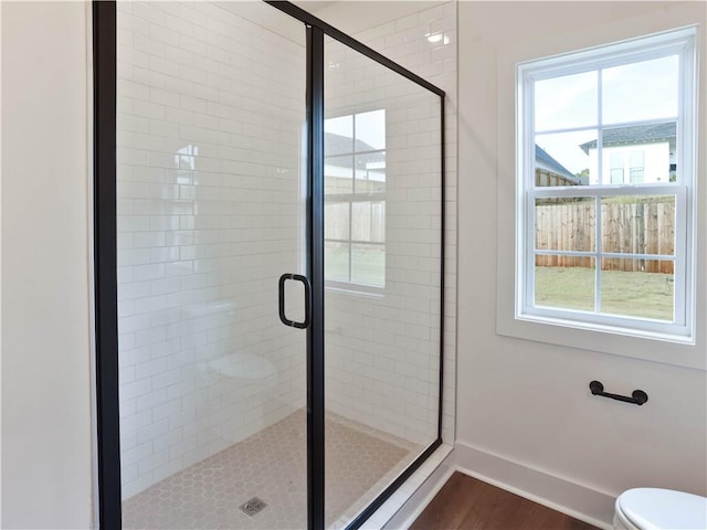 bathroom with plenty of natural light, a stall shower, and baseboards