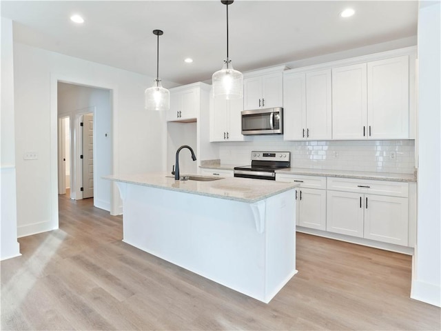 kitchen with a sink, backsplash, appliances with stainless steel finishes, and light wood finished floors