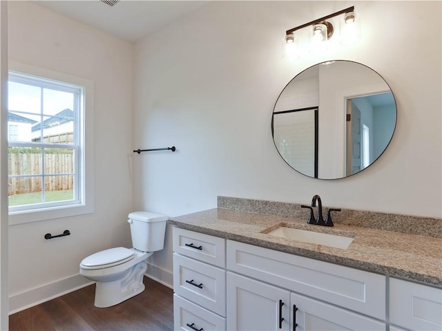 bathroom with baseboards, toilet, wood finished floors, and vanity