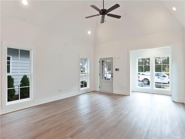 unfurnished living room featuring baseboards, high vaulted ceiling, wood finished floors, and a ceiling fan