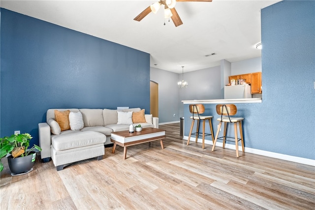 living room with ceiling fan with notable chandelier and light wood-type flooring