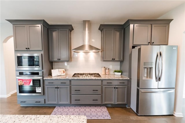 kitchen featuring gray cabinetry, wall chimney range hood, and stainless steel appliances