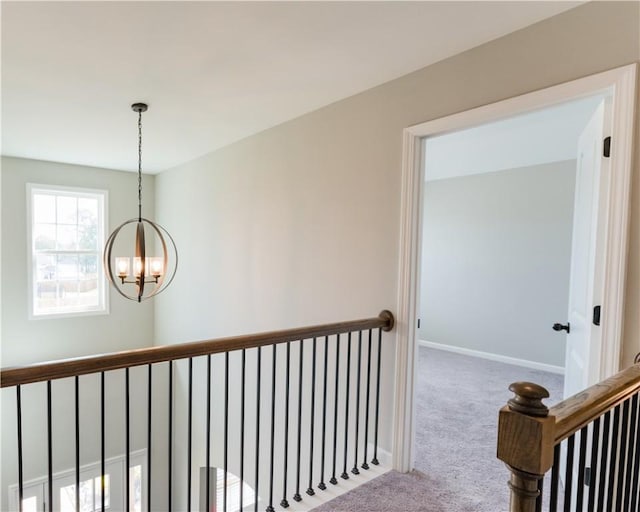 hallway with a notable chandelier and carpet floors