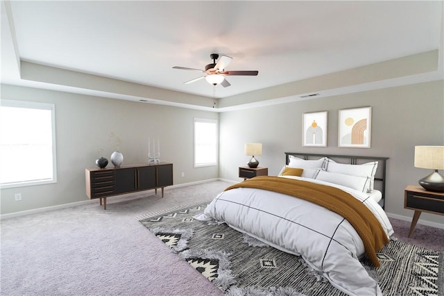 carpeted bedroom featuring a tray ceiling and ceiling fan