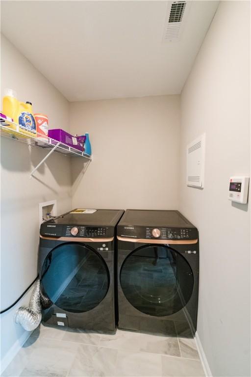 clothes washing area with light tile patterned flooring and independent washer and dryer