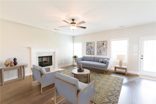 living room featuring plenty of natural light, ceiling fan, dark hardwood / wood-style flooring, and a tile fireplace