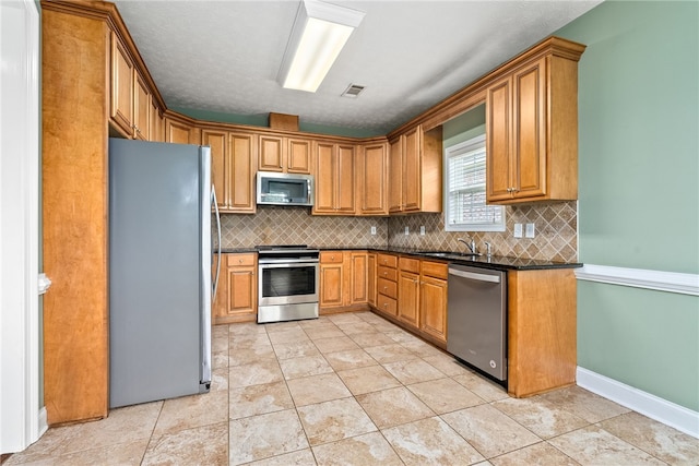 1317 Tulip Ct, Auburn, AL 36830 - kitchen featuring stainless steel appliances, dark countertops, decorative backsplash, brown cabinets, and light tile patterned flooring
