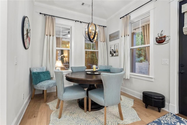 dining area featuring light hardwood / wood-style floors, ornamental molding, and an inviting chandelier