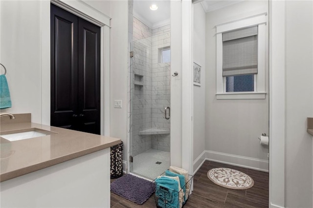 bathroom featuring a shower with shower door, ornamental molding, and vanity