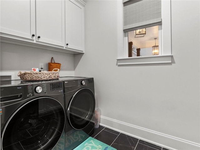clothes washing area featuring cabinets, dark tile patterned floors, and washing machine and clothes dryer