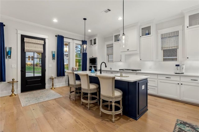 kitchen featuring white cabinets, hanging light fixtures, a healthy amount of sunlight, and an island with sink