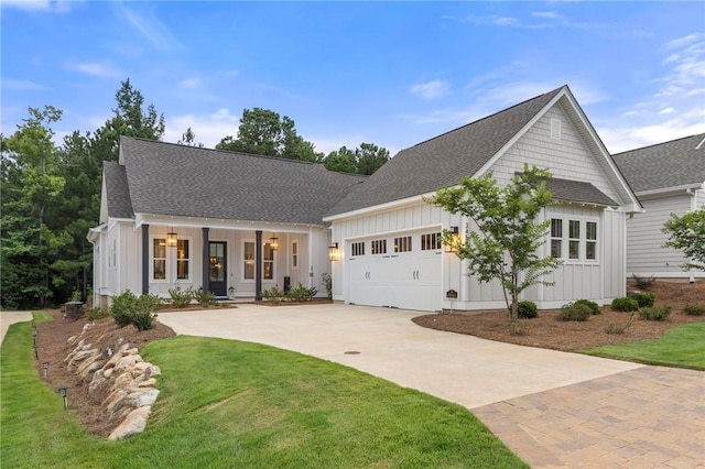 view of front of home with covered porch, a garage, and a front lawn