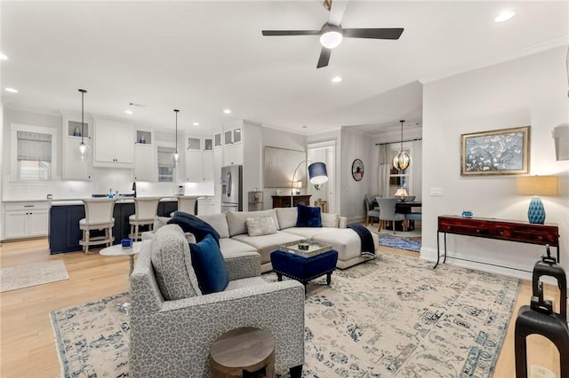 living room with light hardwood / wood-style flooring, ceiling fan, and ornamental molding