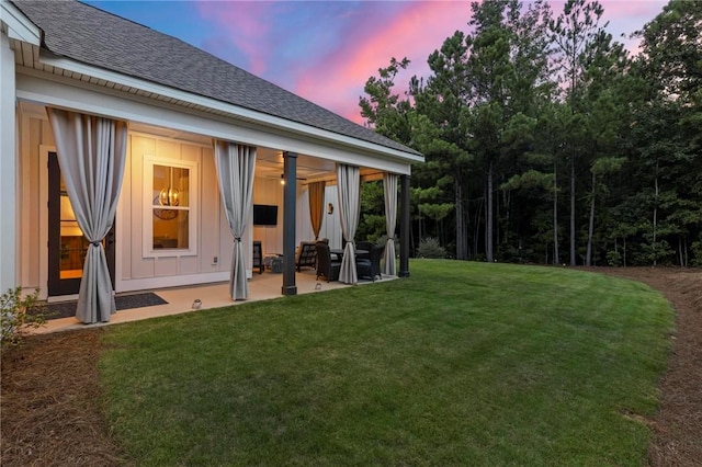 back house at dusk with a yard and a patio
