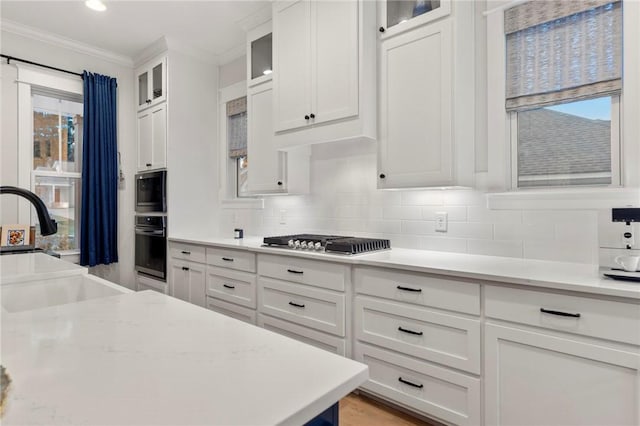 kitchen with sink, crown molding, decorative backsplash, appliances with stainless steel finishes, and white cabinetry