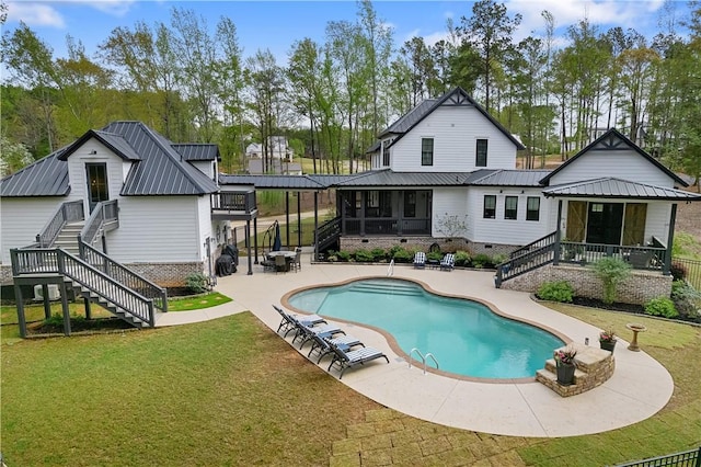 back of property featuring a sunroom, stairway, metal roof, a patio, and a yard